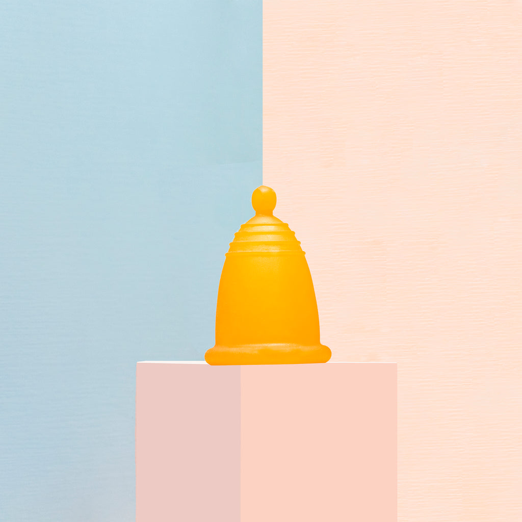 Una copa menstrual naranja en tallas especiales: chica, mediana y grande